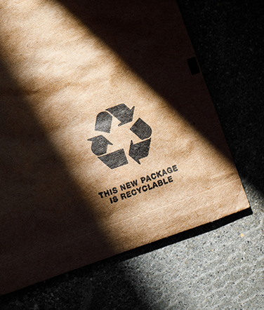 The recycling icon is bathed in sunlight on an Amazon paper padded mailer