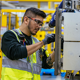 A person wearing safety gear inspects a machine.