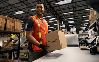 A person stands holding an Amazon box.